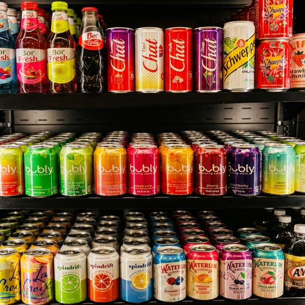 A refrigerated display case filled with rows of colorful bottled and canned beverages.
